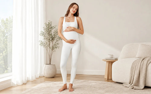 Pregnant woman wearing white maternity leggings in a bright, neutral living room, illustrating a comfortable fit around the belly and legs